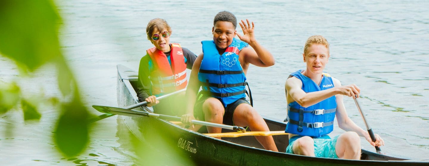 Three boys canoeing on the lake at Waziyatah
