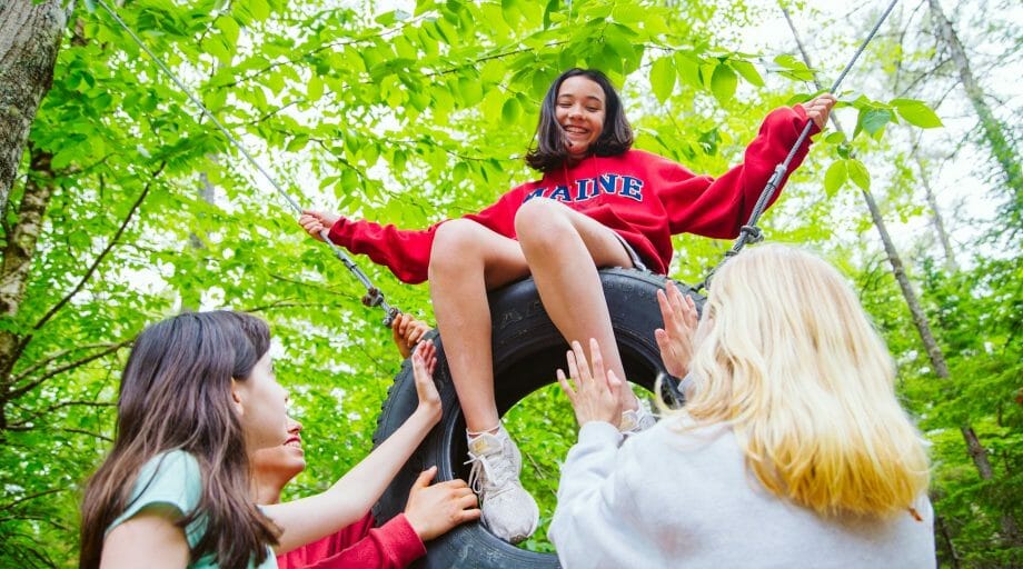 Girls helping camper on challenge course