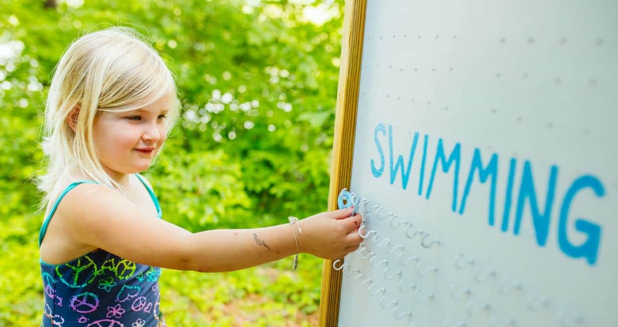 Girls marking down which swimming activity they are doing at McWain Pond