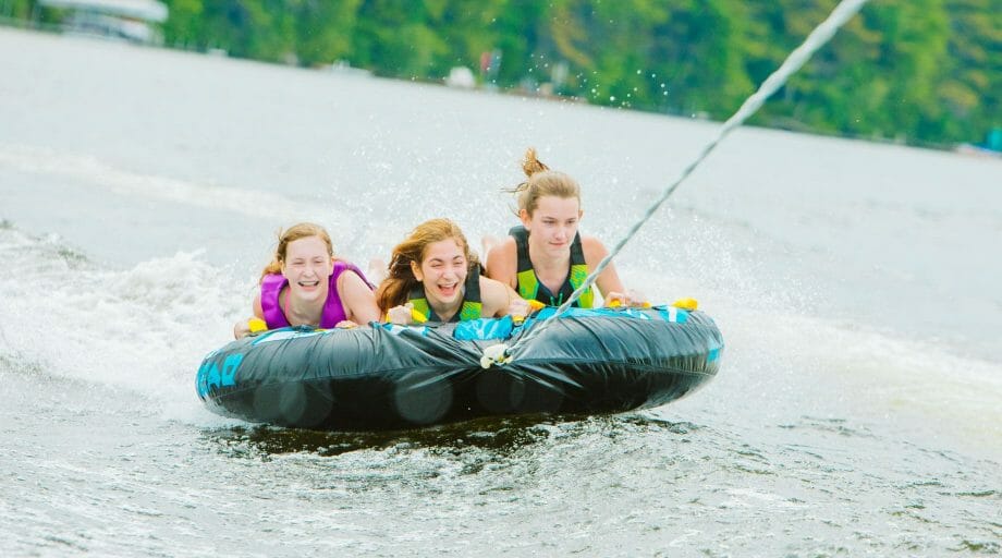 3 girls water tubing on the lake