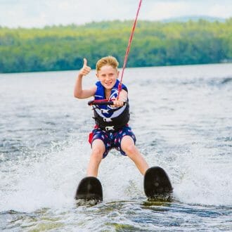 Boy waterskiing and giving thumbs up at McWain Pond