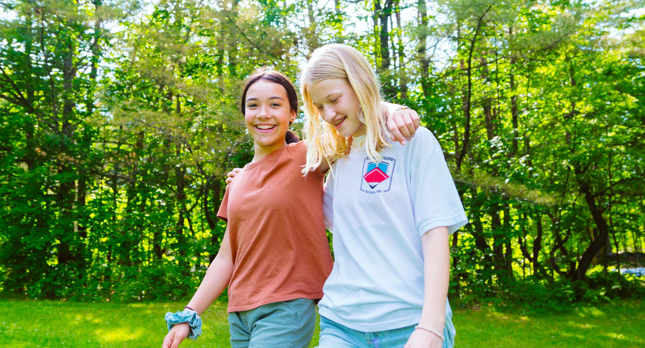 Two CIT girls walking outside with arms around each other at Wazi