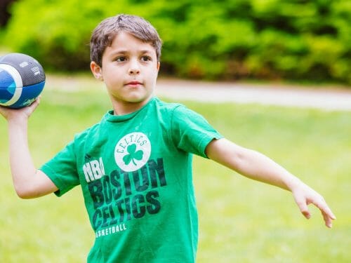 Young boy playing football at Camp Waziyatah