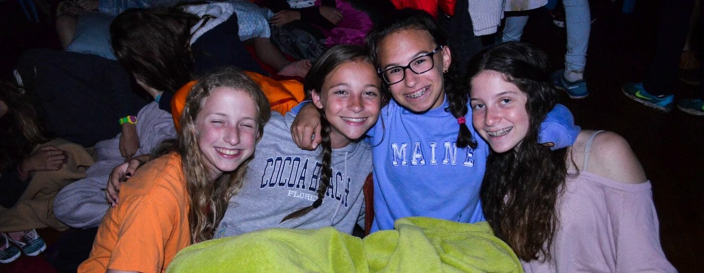 Four girls in sleeping bags at a special events sleepover at Camp Waziyatah