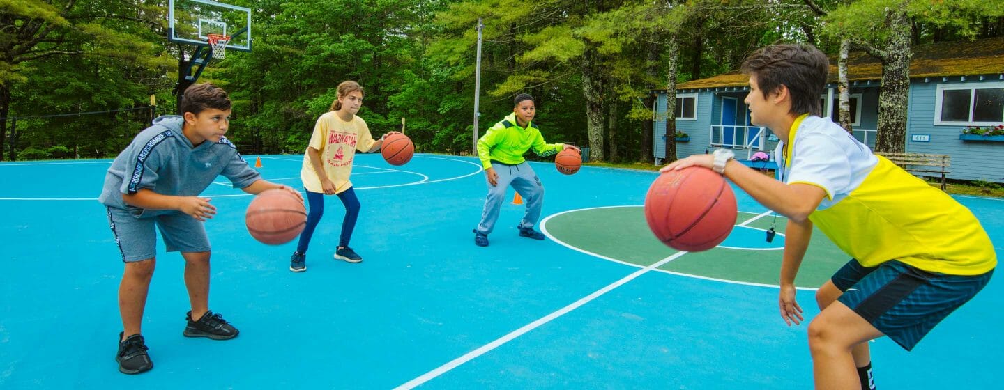 Basketball instructor teaching campers dribbling techniques