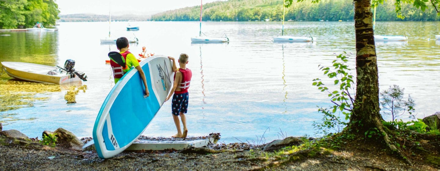 Two campers putting a stand up paddleboard in the lake