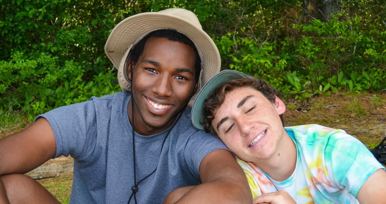 Two campers smiling and sitting outdoors