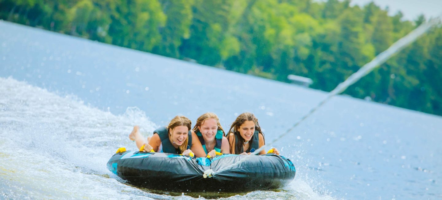 Three girls water tubing on lake